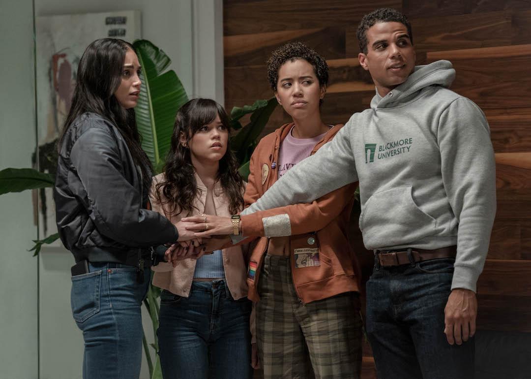 Actors Melissa Barrera, Jenna Ortega, Jasmin Savoy Brow, and Mason Gooding put their hands in the center of a circle in 'Scream VI.'