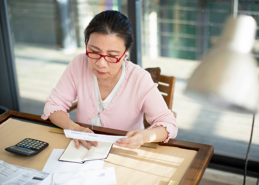 A senior woman reviews financial statements.