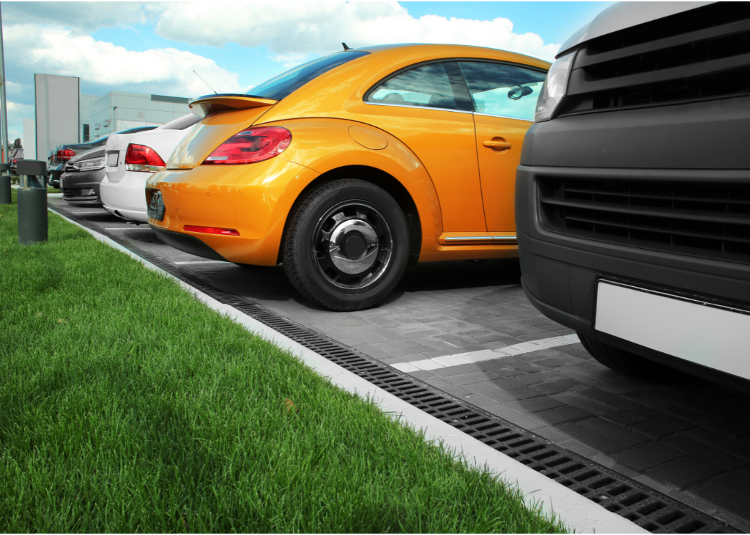 An orange Volkswagen among a line of used cars.