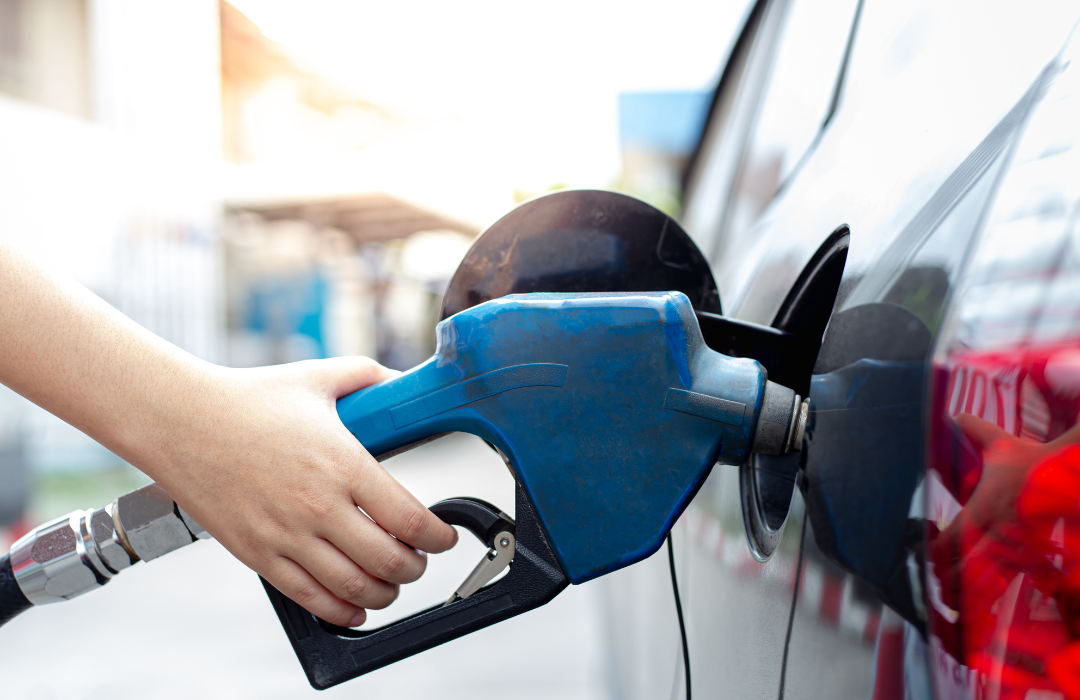 Person's hand filling gas tank of car.