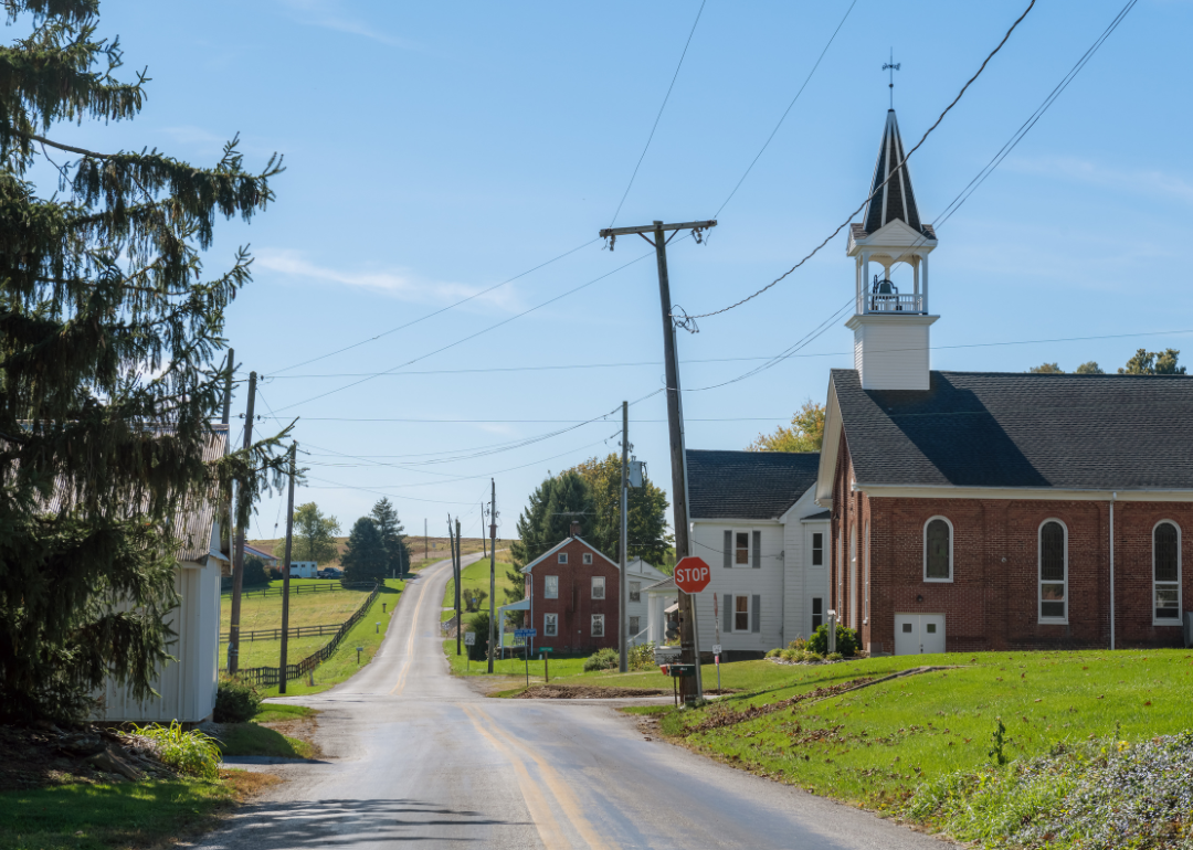 A rural American small town with a two-lane paved road and a church steeple.
