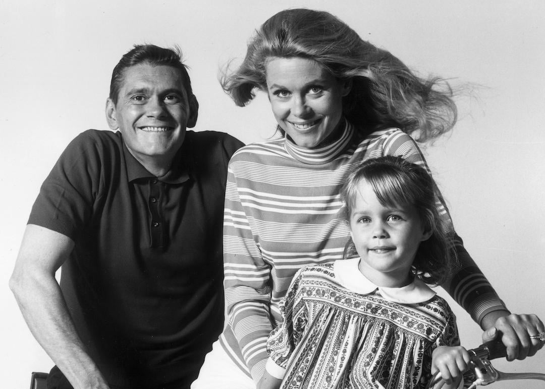 Actors Dick York, Elizabeth Montgomery, and Erin Murphy pose on a bicycle in a promotional portrait for the television series 'Bewitched.'