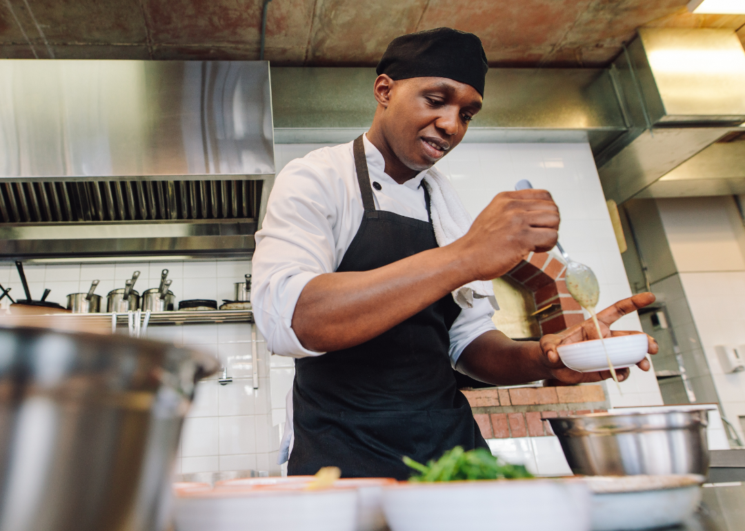 Chef mixes sauces in restaurant kitchen.