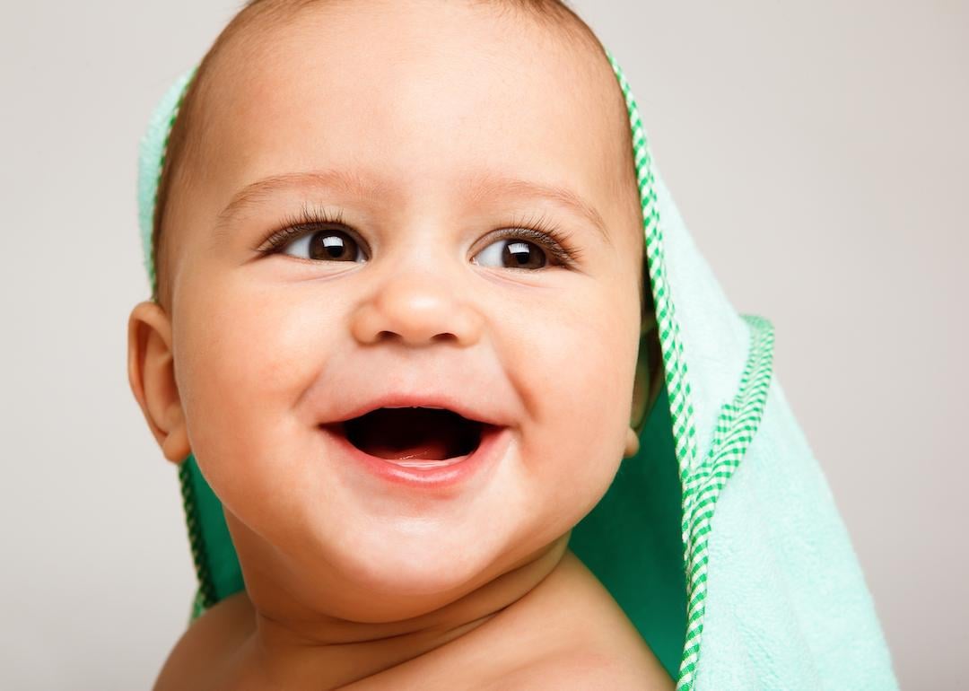 Smiling toothless baby wrapped in a green bath towel.