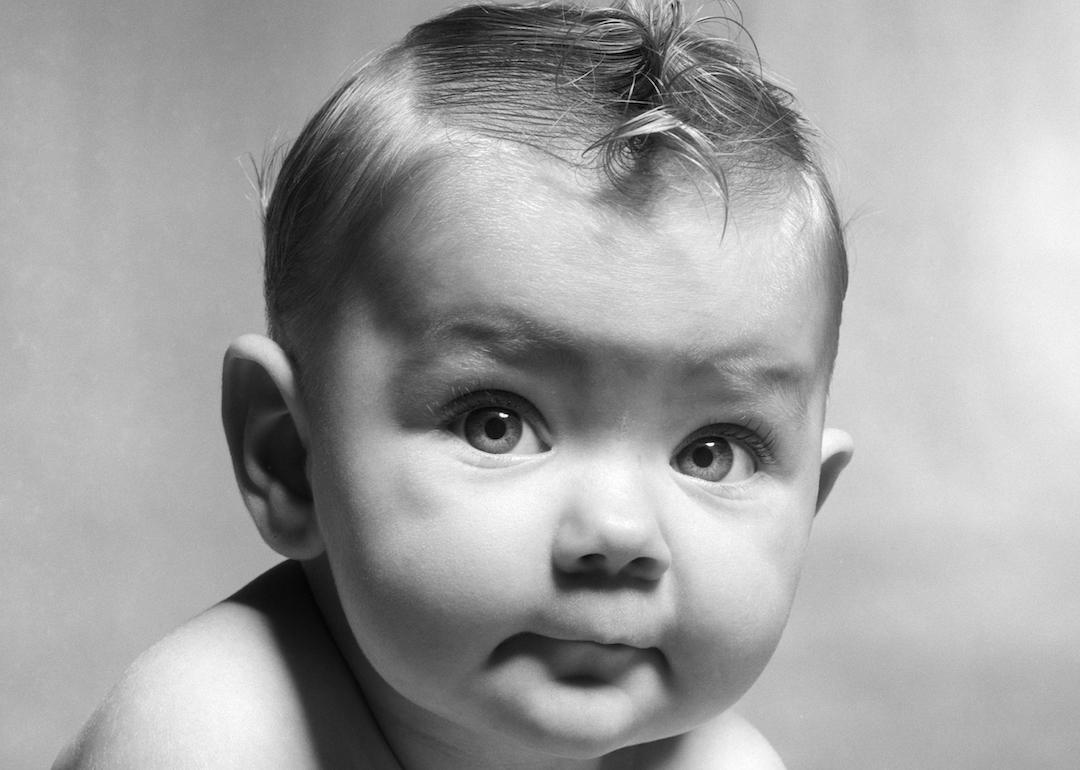 Black and white photo of a baby in the 1950s staring at the camera.