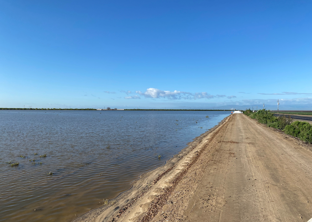 A flooded farm with a dirt road running alongside it