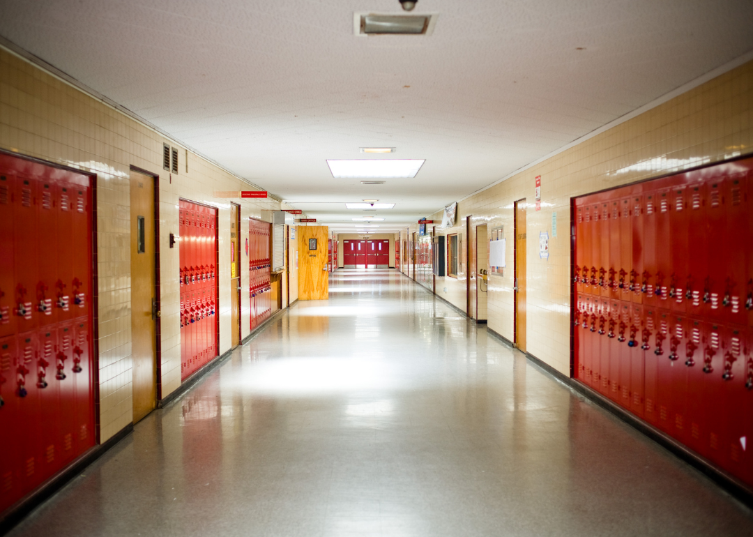 Empty school hallway with red lockers along the walls