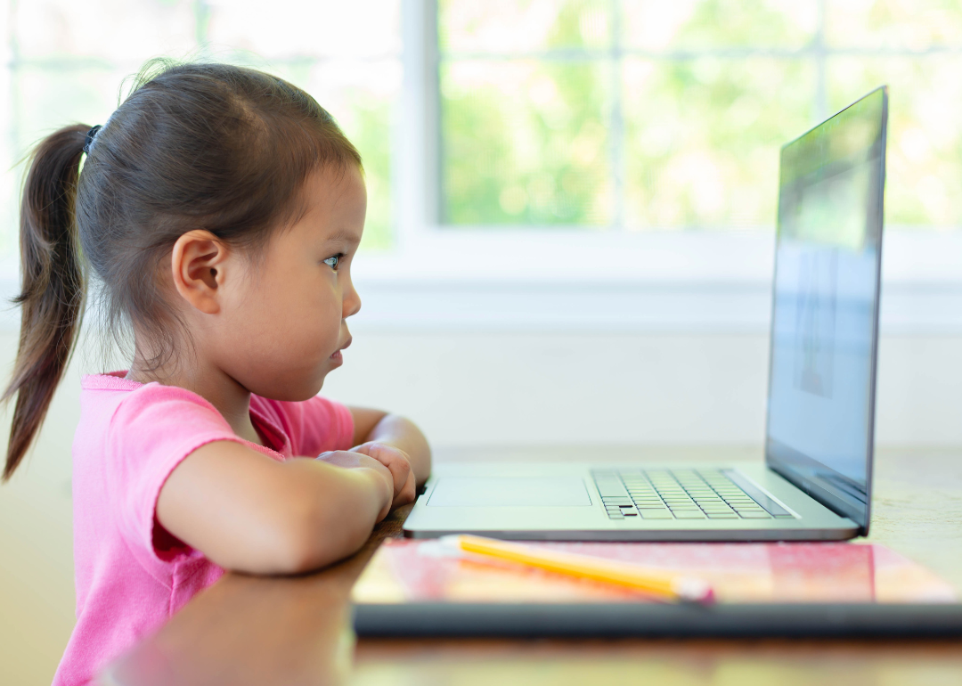 A young girl sits in front of a laptop