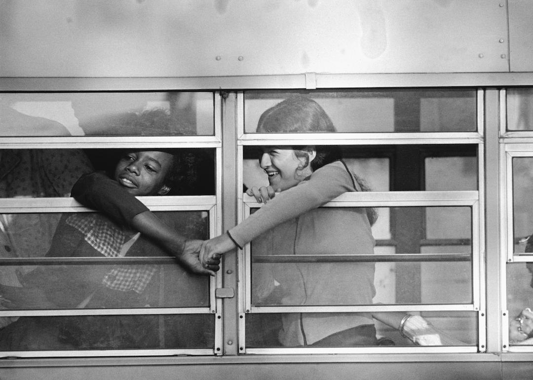 A black student and a white student grasp hands through window as the bus pulled up in front of Charlestown High School in Boston in 1975.