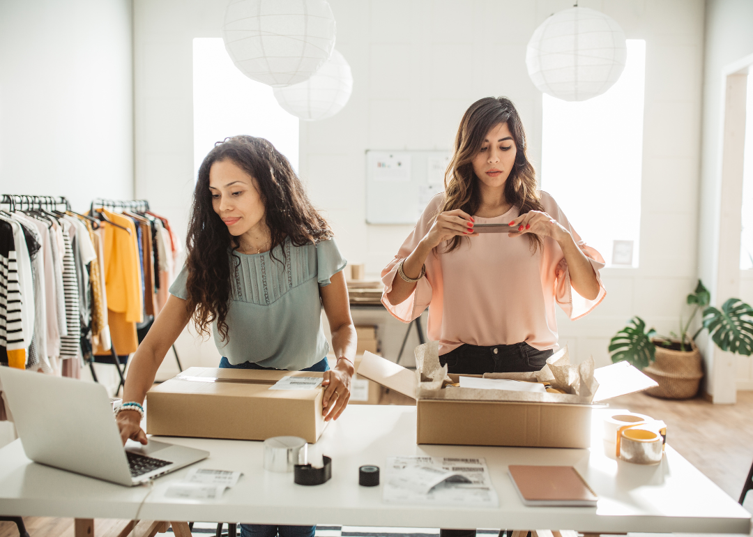 Two women at counter wrapping packages in a small business setting