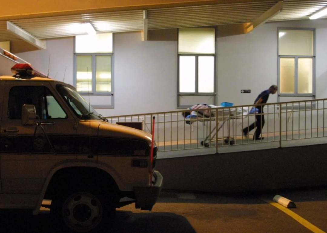 An ambulance driver walks a gurney up a ramp at a hospital