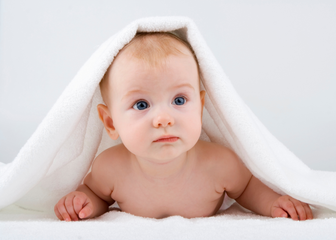 Baby lying on stomach under a white towel