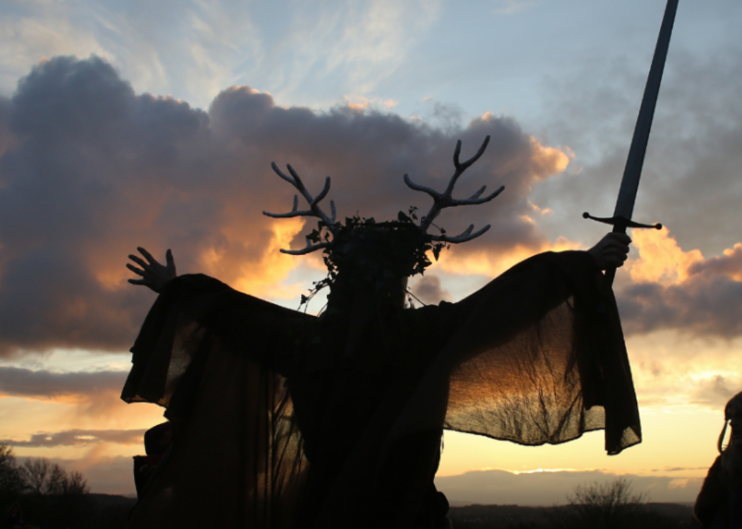 A man representing the Winter King holds a sword as he takes part in a sunset ceremony as they celebrate the Samhain old pagan festival.