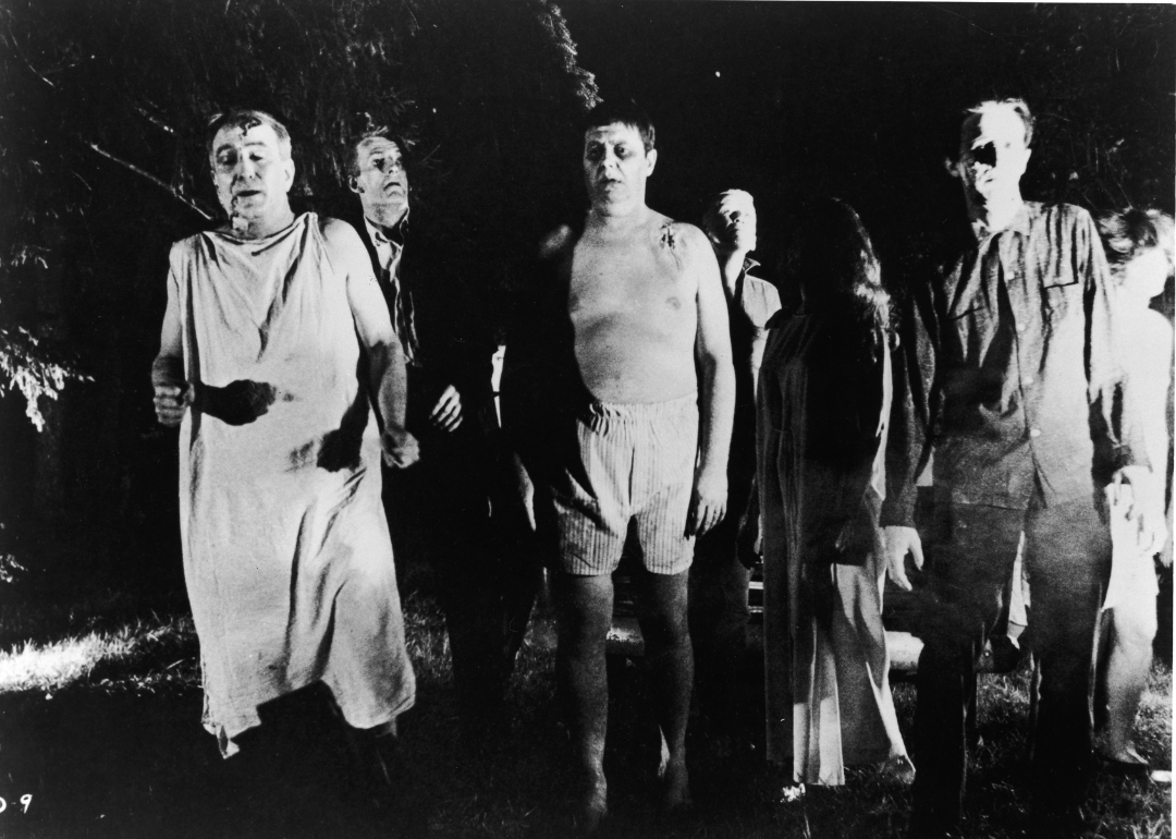 A line of undead 'zombies' walk through a field in the night in a still from the film, 'Night Of The Living Dead,' directed by George Romero, 1968.