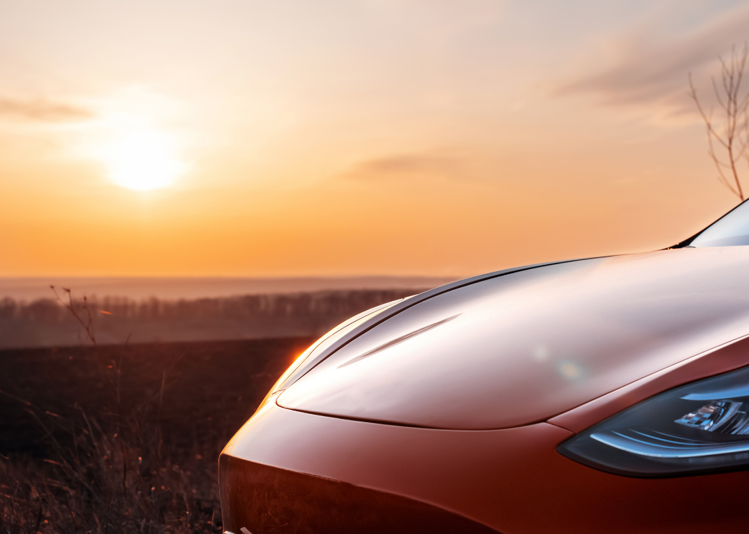 A red Tesla sedan parked in the sunlight