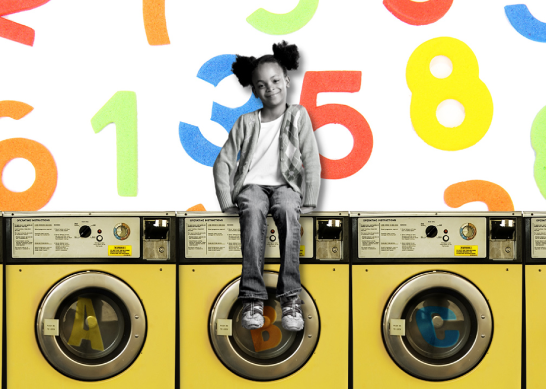 A young girl sits atop a row of washing machines