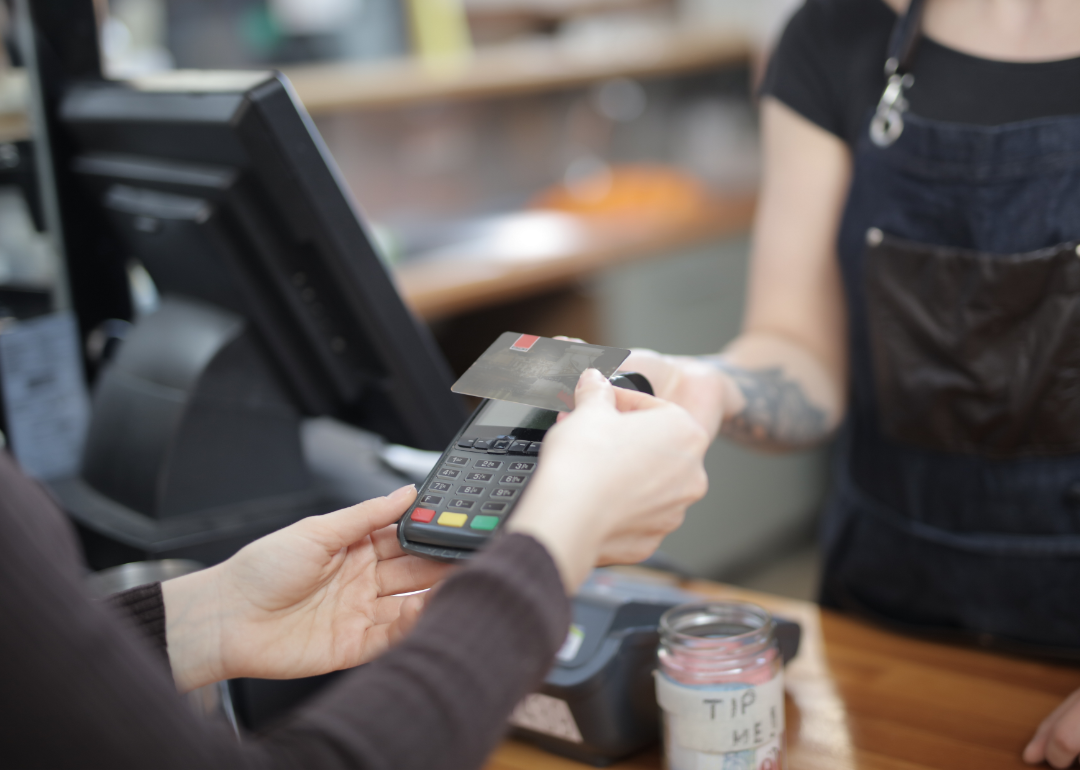 A person pays by credit card at coffee shop register.
