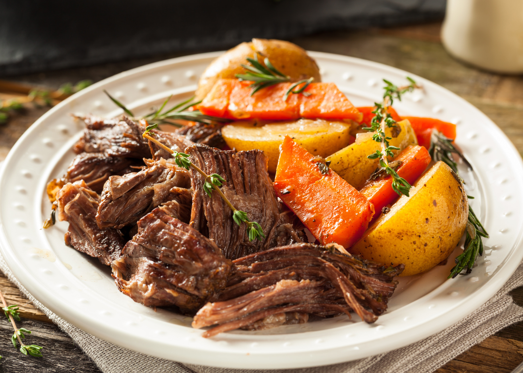 A loaded plate of homemade slow cooker pot roast with carrots and potatoes