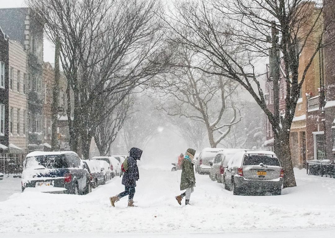 People trek through a snow-covered street in Brooklyn during a blizzard.