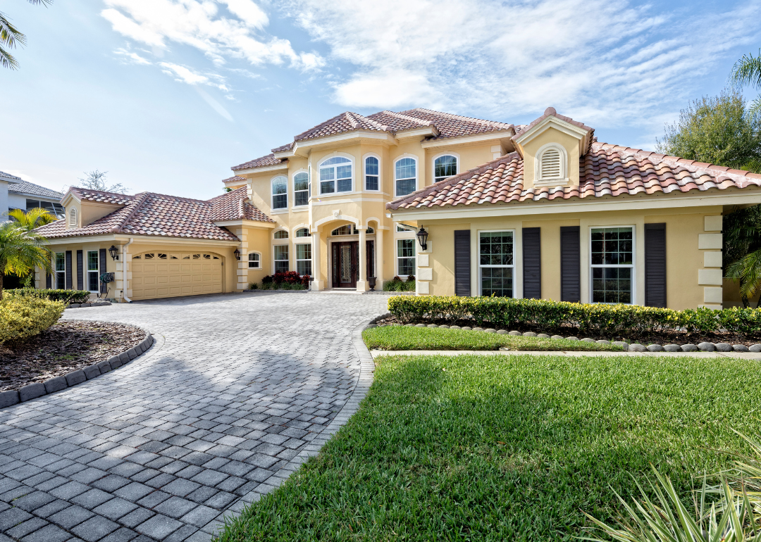 Exterior of a large home with a stucco roof and long paved drive