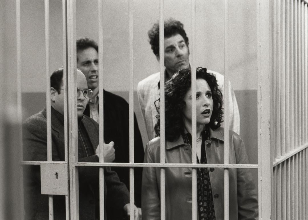 Actors Jason Alexander (George), Jerry Seinfeld (Jerry), Michael Richards (Kramer), and Julia Louis-Dreyfus (Elaine) stand behind bars in a scene from the final episode of 'Seinfeld.'