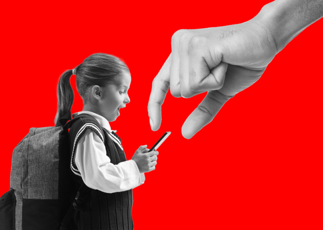 A conceptual image of a large hand taking a smartphone away from a schoolgirl.