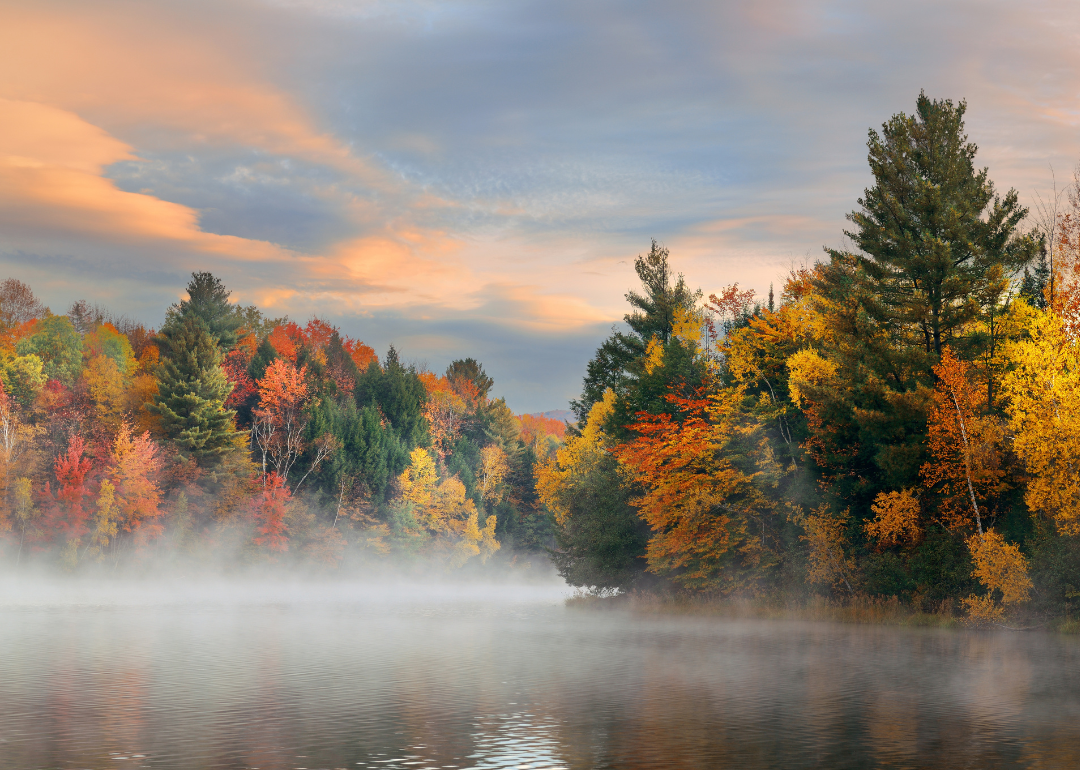 A foggy lake at sunrise surrounded by autumn foliage in Stowe, Vermont