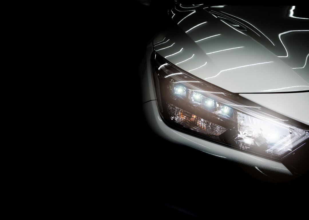 Close-up of a luxury sedan's headlights against a black background