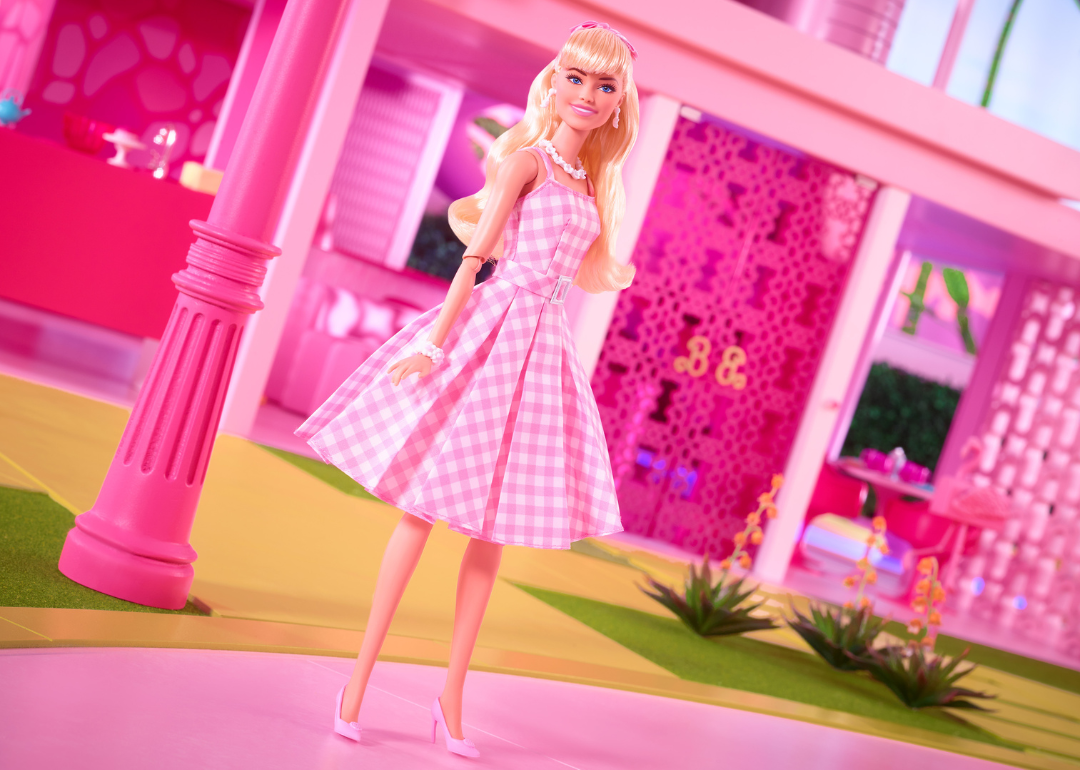A Barbie doll standing in front of the Dreamhouse