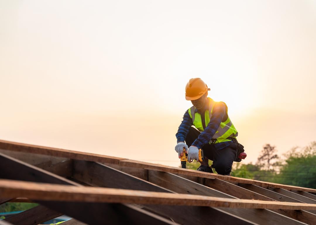 Construction worker installing wooden roof structure.