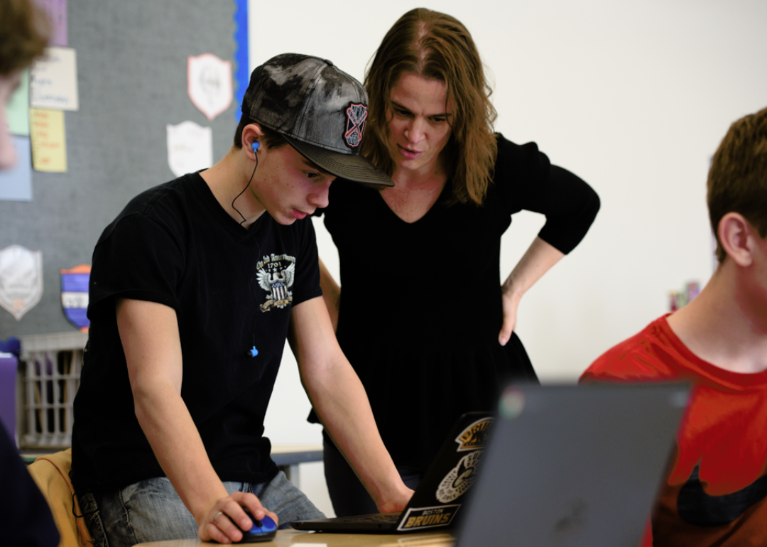 Teacher helping a student on a laptop