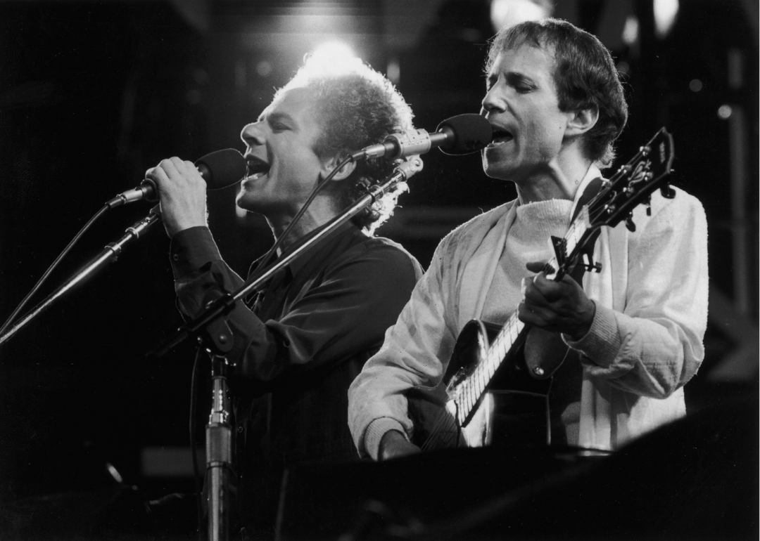  American musicians Art Garfunkel (L) and Paul Simon of the folk duo Simon and Garfunkel perform during a reunion concert at Wembley Stadium, London, England, circa 1982.