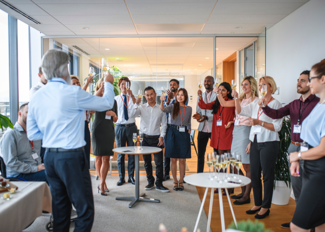A large group of people in a board room toast a new business opening