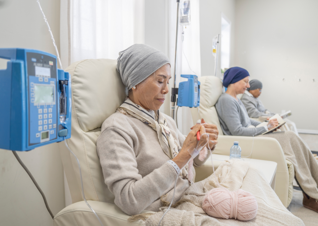 People sitting in chairs while receiving chemotherapy treatment.