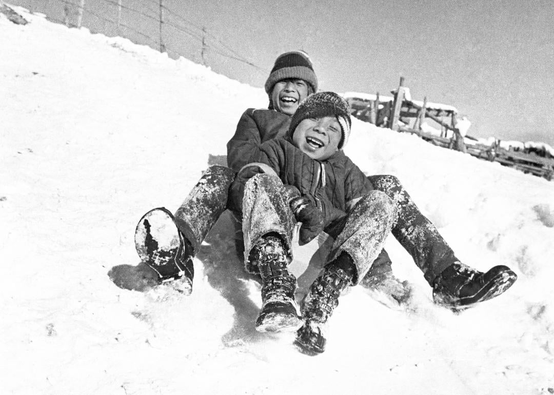 Two children sled down a hill after a snowstorm at Cochiti Indian Pueblo in New Mexico in 1970.