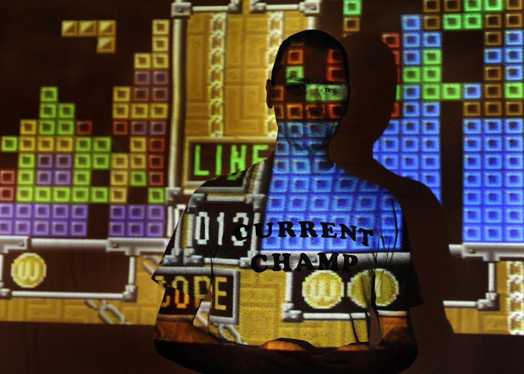 tetris game projected on the wall with player posing in the dark