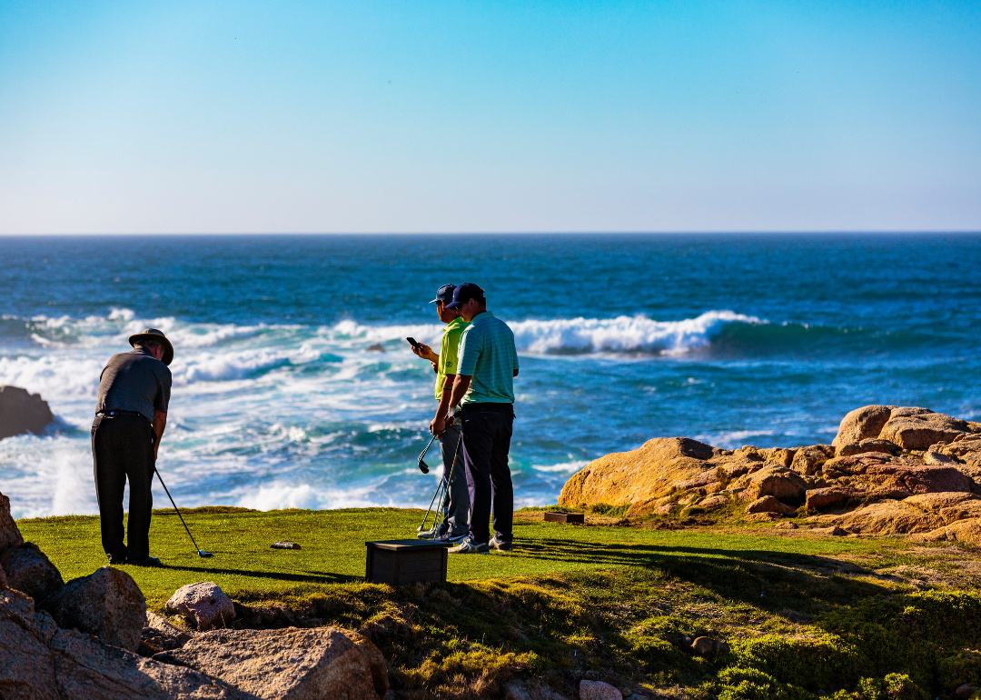3 people playing on a golf course by the Pacific ocean at the Monterey Peninsula Country Club in Del Monte Forest, California