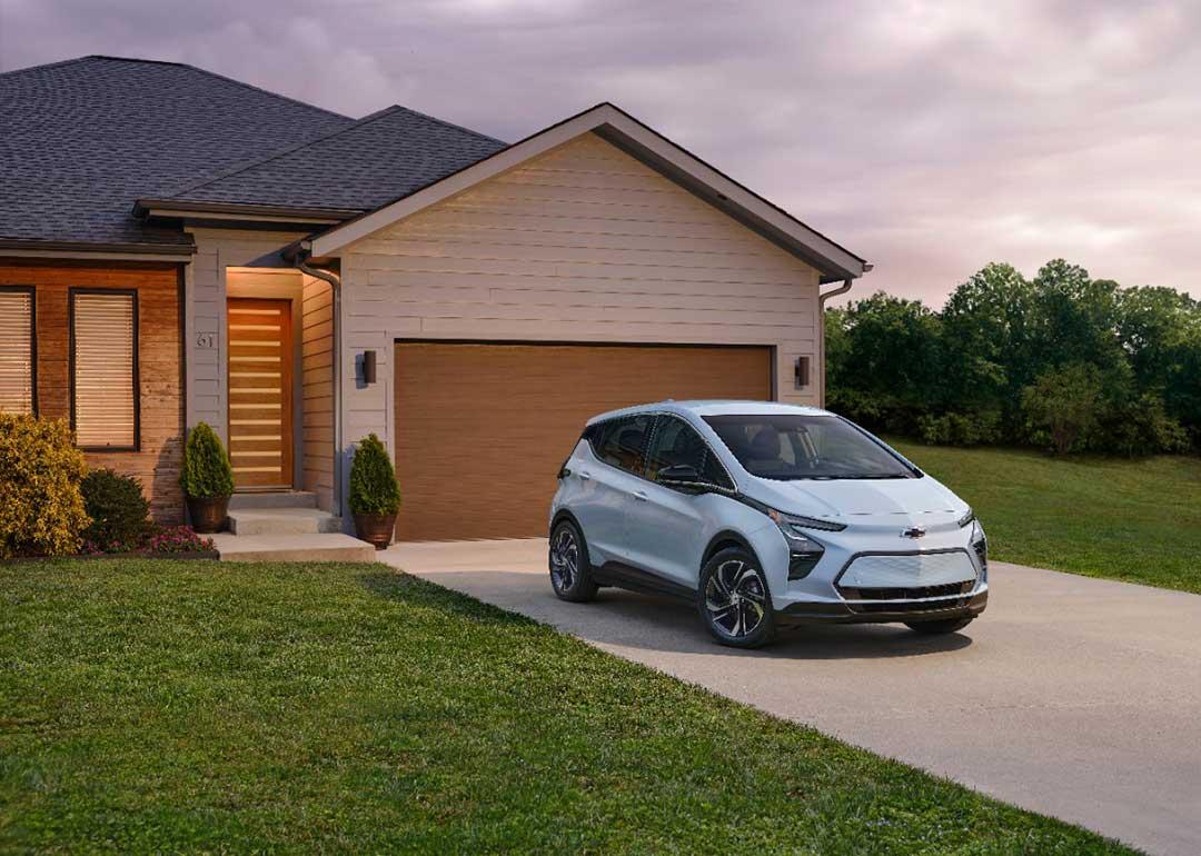 light blue chevy bolt parked in front of house