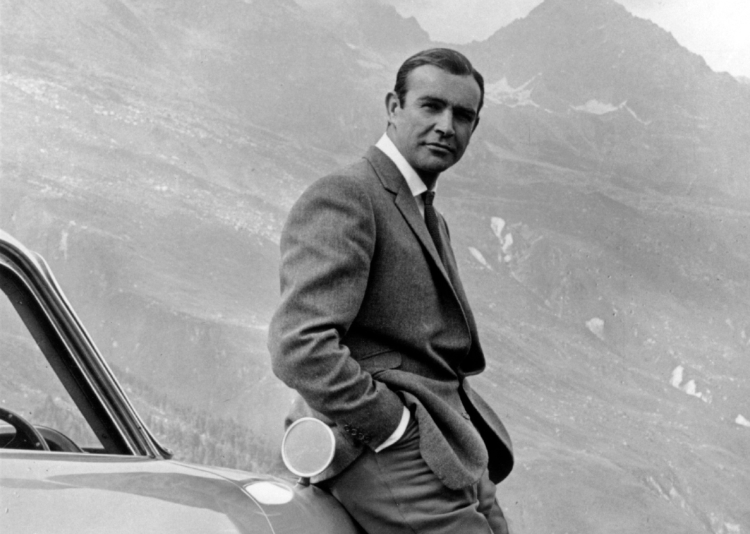 Actor Sean Connery poses as James bond next to his Aston Martin DB5 in a scene from the film 'Goldfinger,' 1964