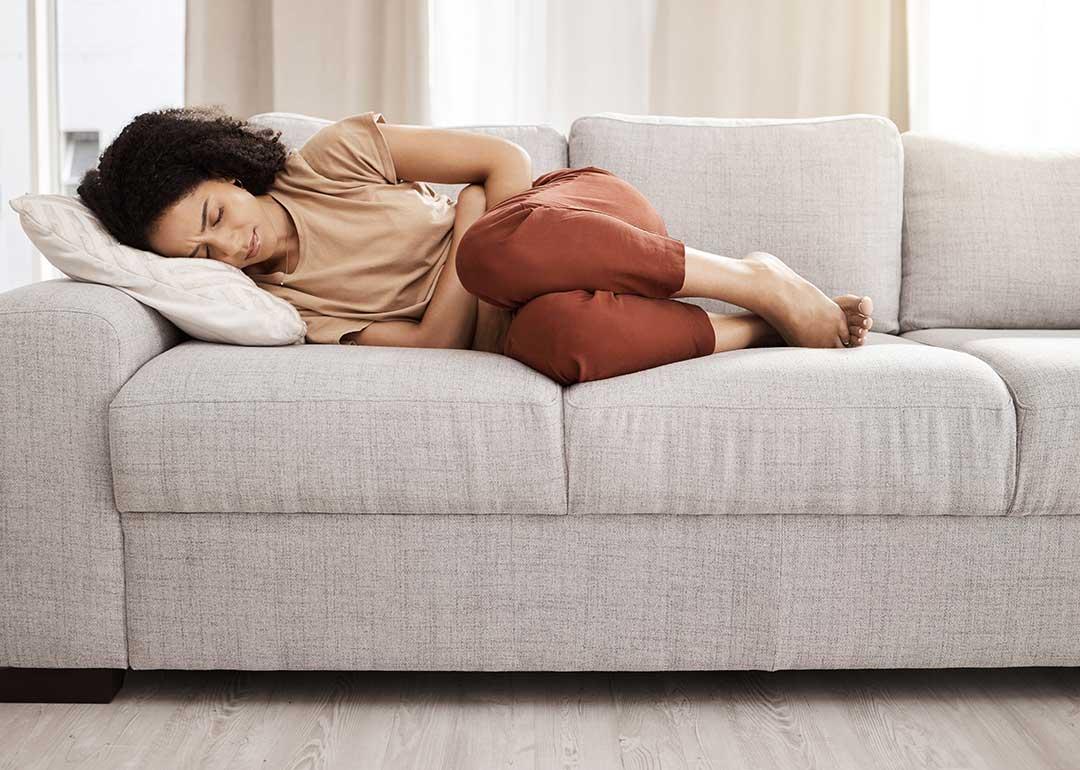 woman curled up on couch from pain