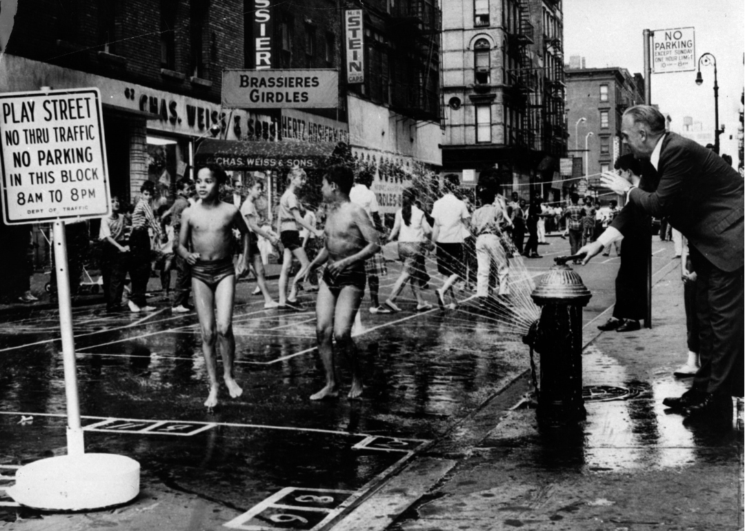 Chief of Police Kennedy opens up a fire hydrant, spraying water over children playing in Hester Street, a designated 'play street' closed to traffic, during the hot New York summer of 1960. 