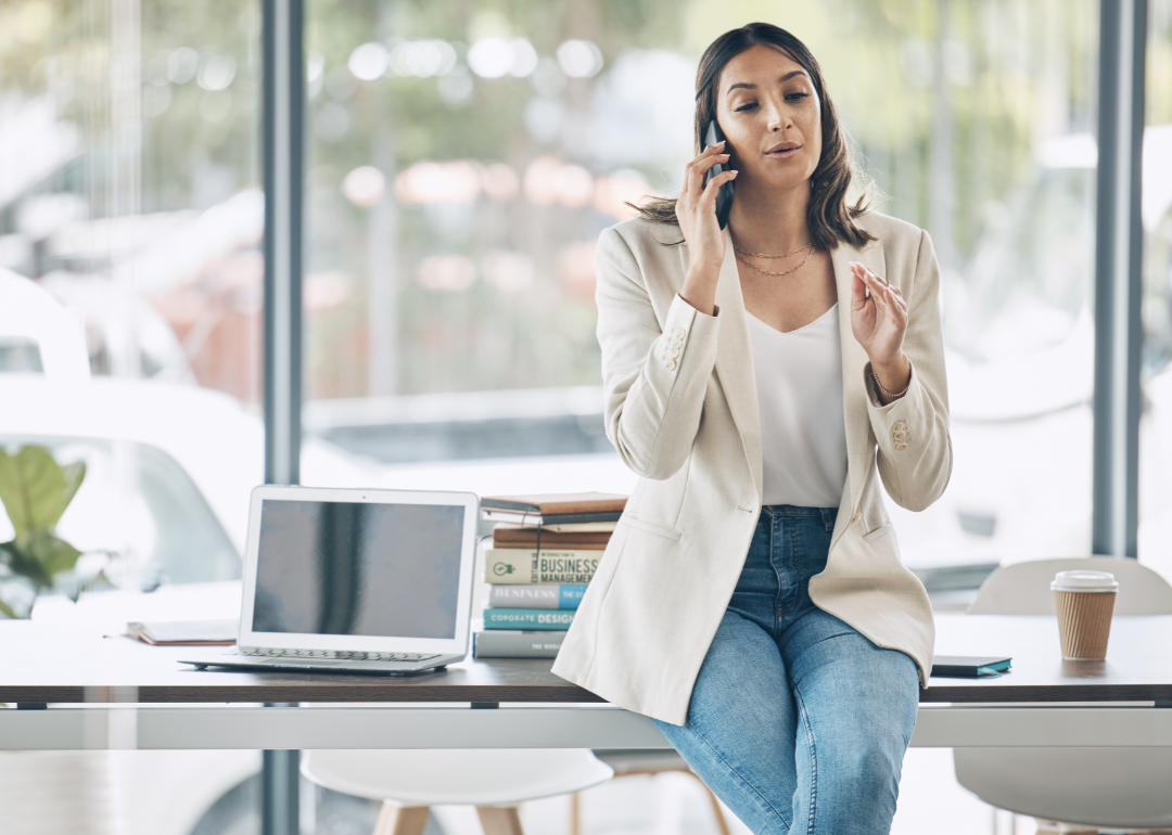 business woman on the phone with business books on desk in background