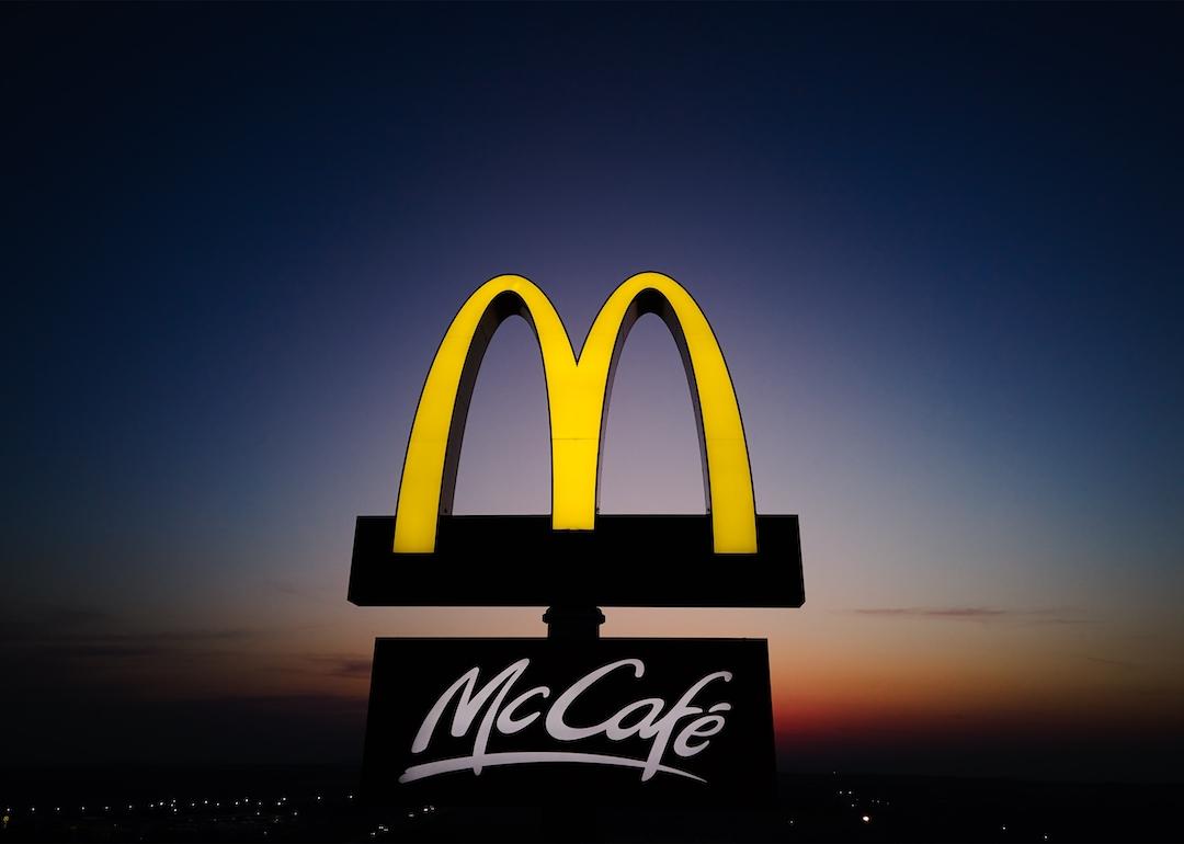 Glowing McDonalds restaurant sign against night sky.