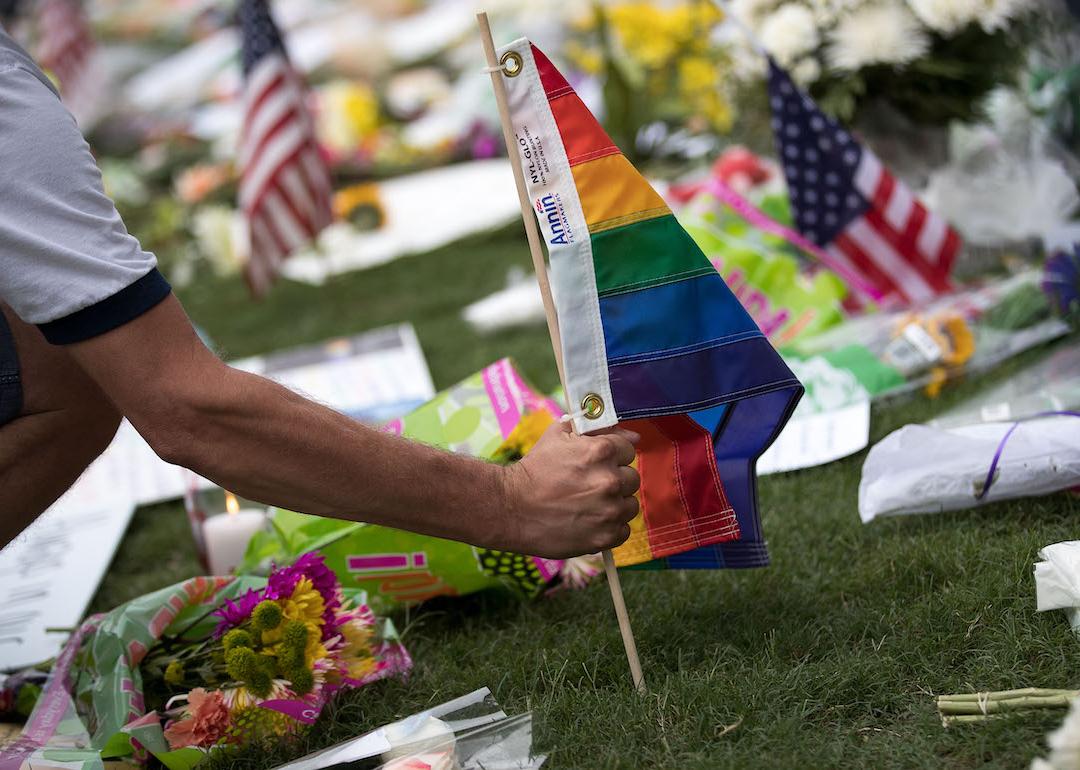 A person plants a pride flag at a makeshift memorial before an evening vigil for the victims of the Pulse Nightclub shootings in Orlando, Florida.
