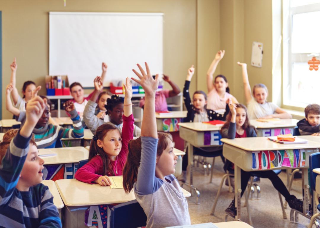 students raising hands in classroom