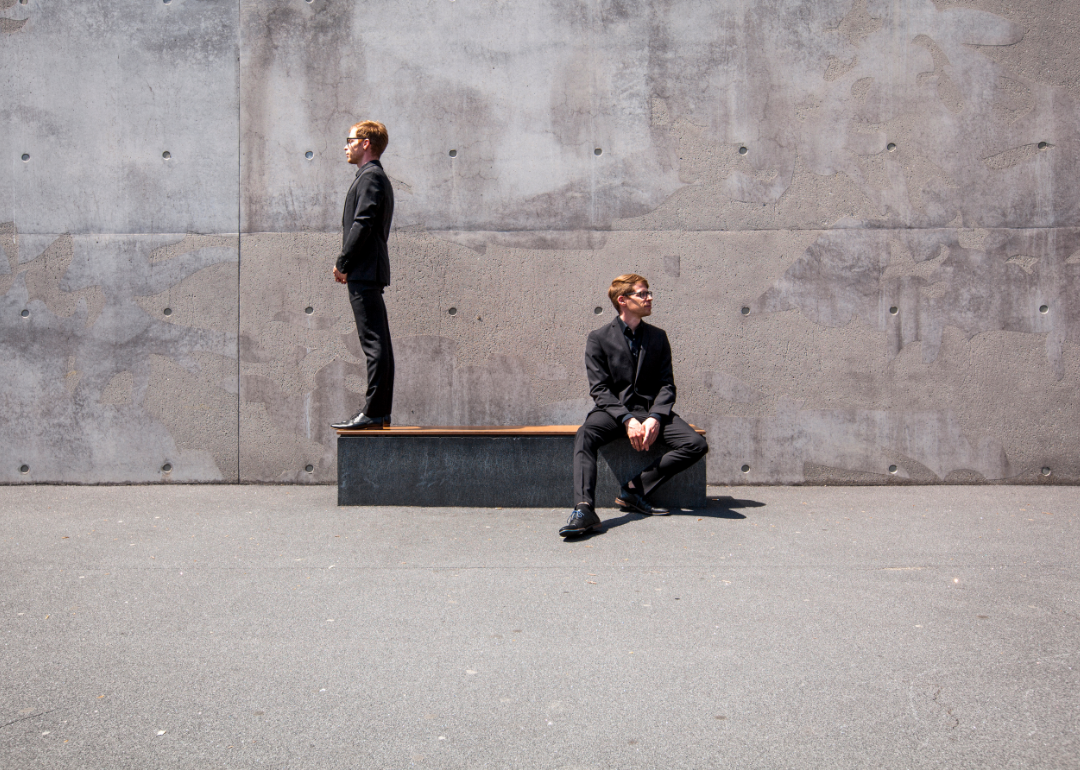 two people face away from each other in disagreement against stark gray concrete background