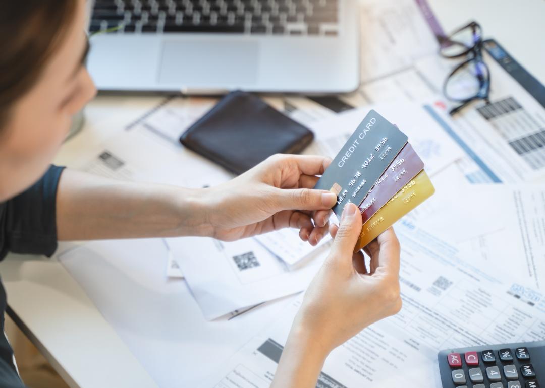 woman looking at credit cards with bills in the background 