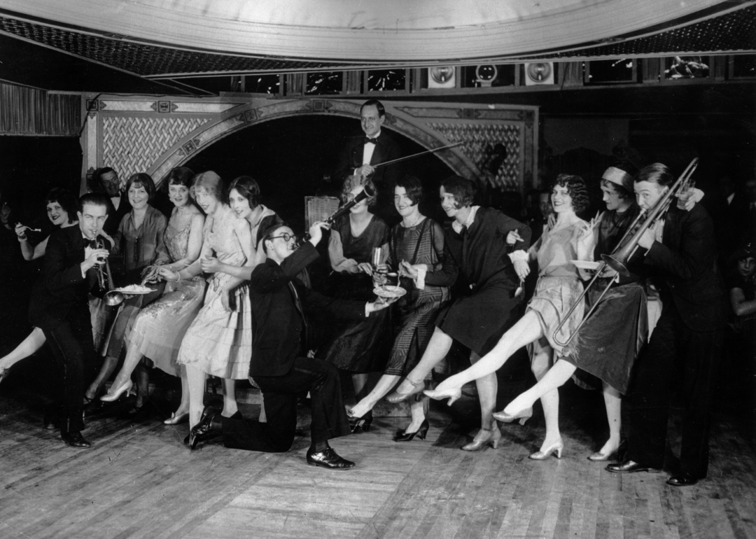 Female flappers kicking, dancing, and having fun while musicians perform during a Charleston dance contest at the Parody Club.