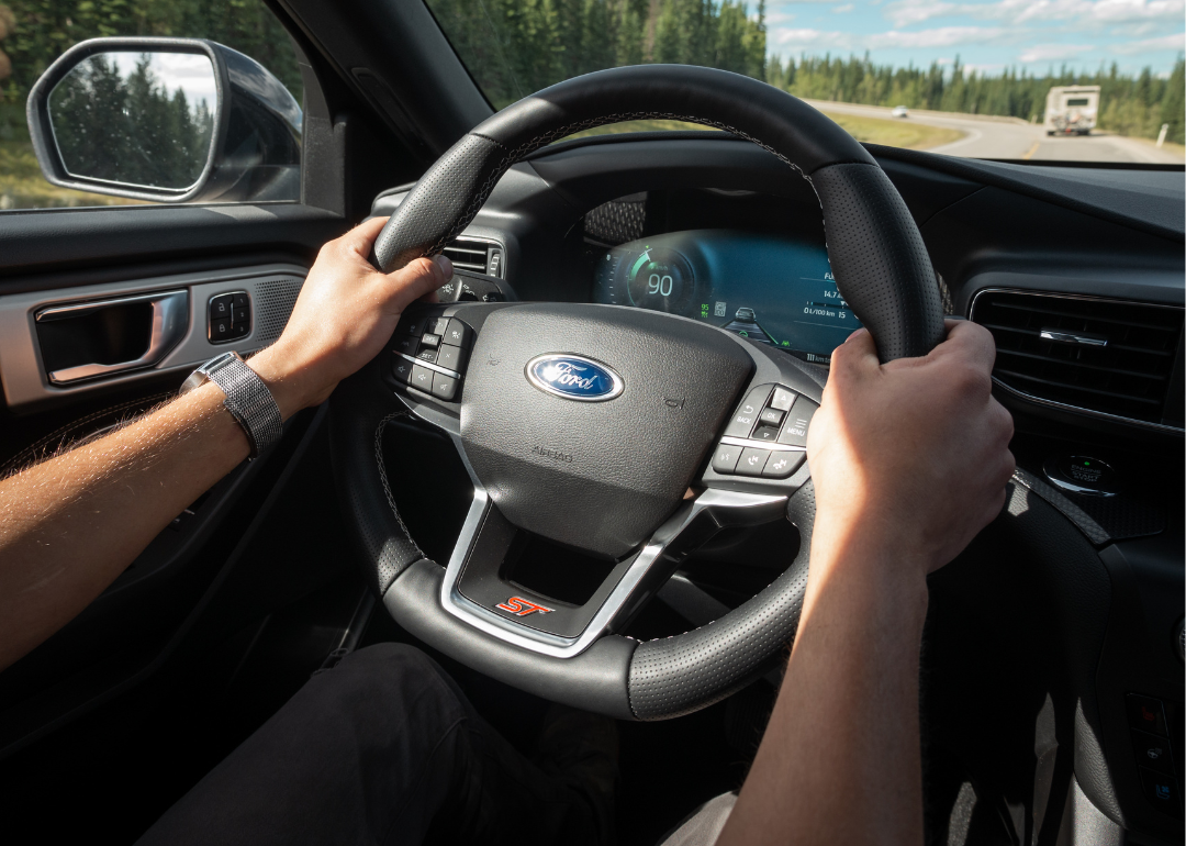 Hands holding the steering wheel of a Ford vehicle
