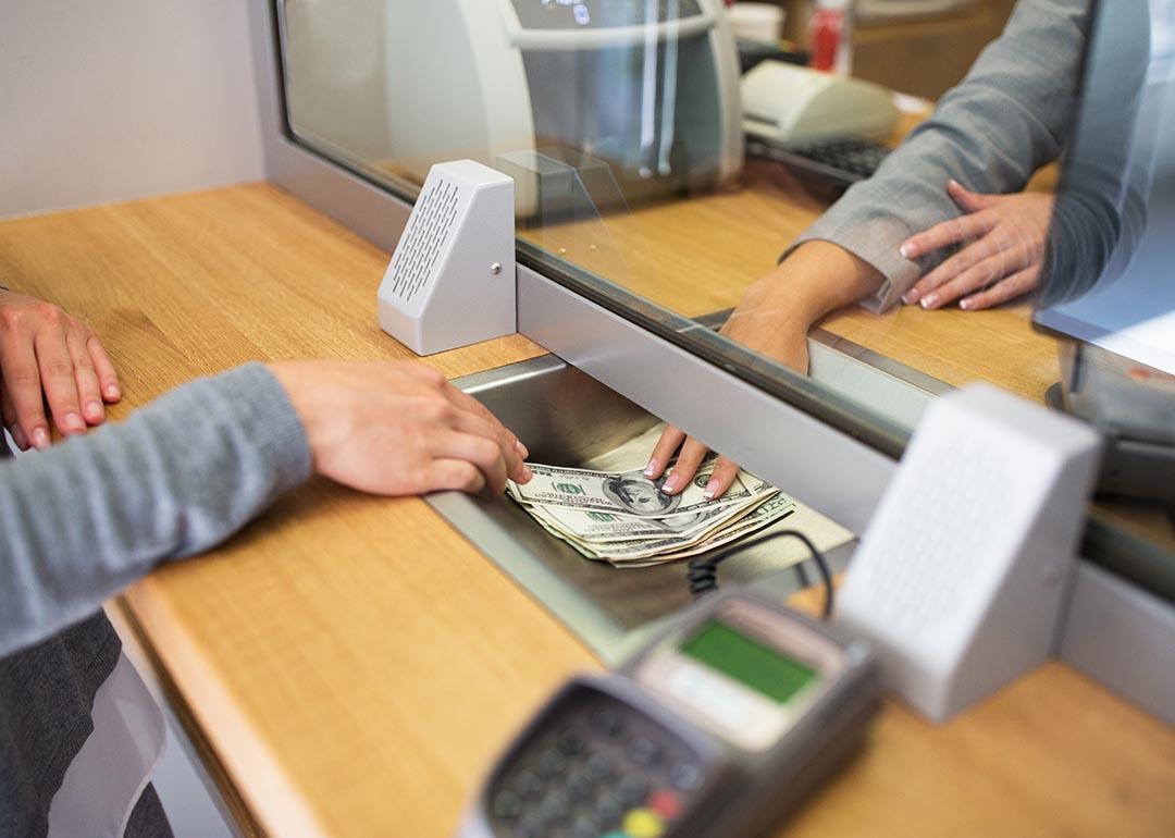 View of cash exchange in window between hands of teller and bank customer